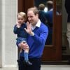 Le prince George de Cambridge dans les bras de son père William pour aller découvrir sa petite soeur la princesse Charlotte à la maternité Lindo, le 2 mai 2015, à Londres