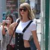 Taylor Swift se promène à New York, le 28 mai 2015. Elle porte une salopette noire, un tee-shirt court et un sac de la marque Gucci.