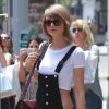 Taylor Swift se promène à New York, le 28 mai 2015. Elle porte une salopette noire, un tee-shirt court et un sac de la marque Gucci