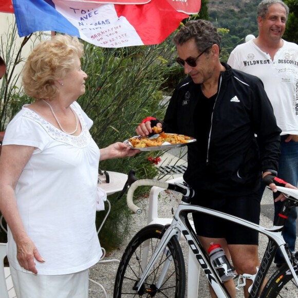 L'ancien président de la République, Nicolas Sarkozy, se fait offrir des beignets de fleurs de courgette à l'auberge de Ginette lors d'une sortie en vélo dans la forêt des Maures Le Lavandou, le 7 juillet 2014.