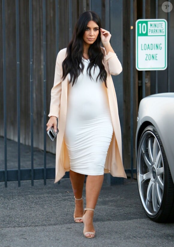 Kim Kardashian quitte un studio de tournage à Van Nuys, Los Angeles, habillée d'une veste nude Maison Margiela, d'une robe blanche Wolford et de sandales Manolo Blahnik (modèle Chaos). Le 27 juillet 2015.