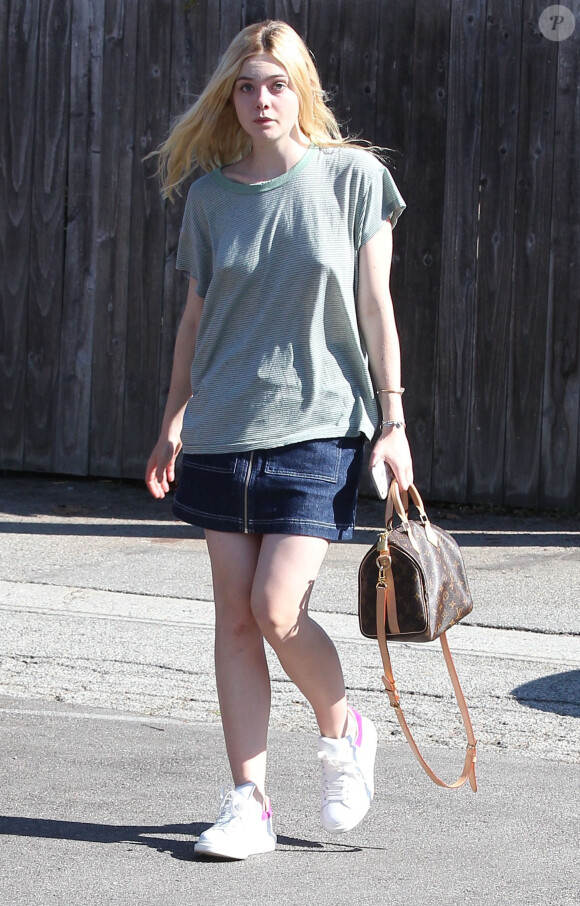 Elle Fanning se rend chez le coiffeur à Beverly Hills, habillée d'un t-shirt raté, d'une jupe en denim brut et de baskets Alexander McQueen. L'actrice de 17 ans tient à la main un sac Louis Vuitton (modèle Speedy). Le 24 août 2015.