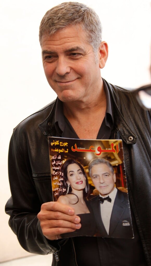 George Clooney qui tient un magazine où il est en couverture avec sa femme Amal Alamuddin Clooney - conférence de presse pour le film "Tomorrowland" le 8 mai 2015 au Montage Hotel, à Beverly Hills.