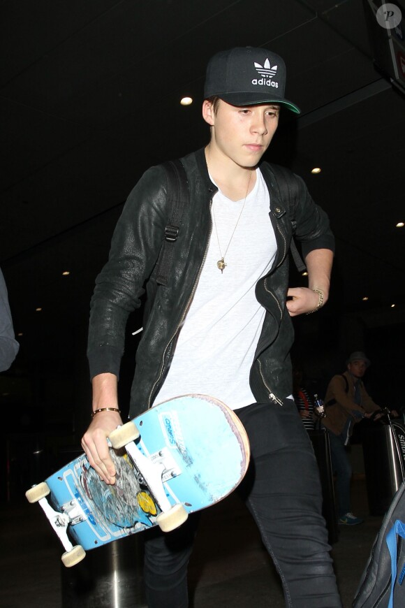 Brooklyn Beckham, armé de son skateboard, arrive à l'aéroport de Los Angeles le 23 octobre 2015.