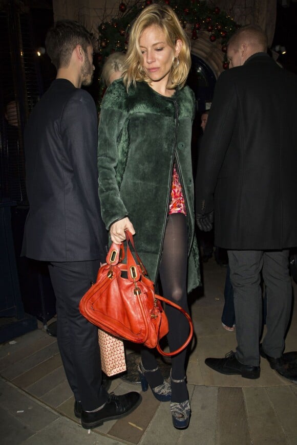 Sienna Miller quitte la soirée de Noël du magazine LOVE à Londres, habillée d'un manteau Burberry et tenant un sac Chloé (modèle Paraty). Le 18 décembre 2015.