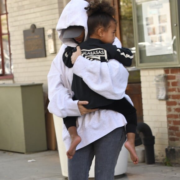 Kim Kardashian, cachée par ses vêtements, et sa fille North sortent de son appartement à New York, le 6 octobre 2016.