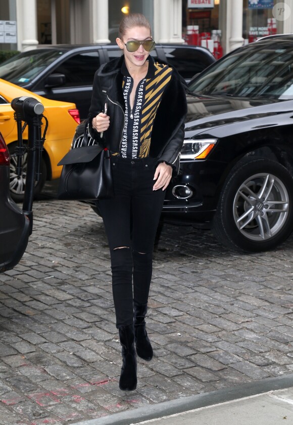 Gigi Hadid à New York, porte une veste en cuir, un polo Versus Versace, un jean noir et des chaussures Stuart Weitzman. Des lunettes de soleil Quay et un sac Mansur Gavriel accessoirisent sa tenue. Le 12 décembre 2016.