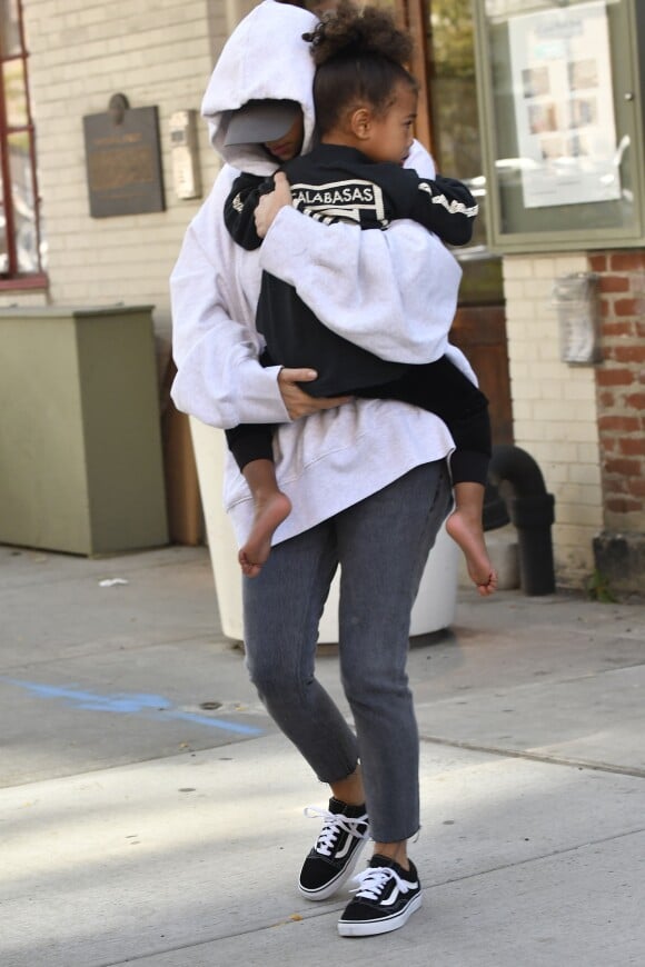Kim Kardashian, cachée par ses vêtements, et sa fille North sortent de son appartement à New York, le 6 octobre 2016