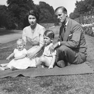 La princesse Elizabeth et le prince Philip, duc d'Edimbourg, en août 1951 avec leurs enfants la princesse Anne et le prince Charles dans le parc de Clarence House à Londres.