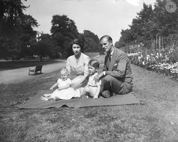 La princesse Elizabeth et le prince Philip, duc d'Edimbourg, en août 1951 avec leurs enfants la princesse Anne et le prince Charles dans le parc de Clarence House à Londres.