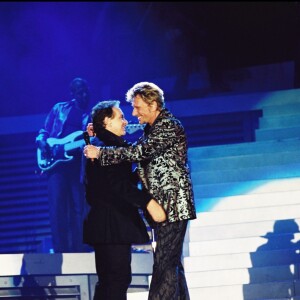 Michel Sardou et Johnny Hallyday sur scène lors d'un concert au Parc de Sceaux, le 16 juin 2000.