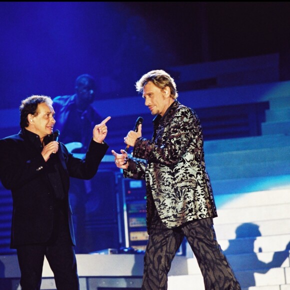Michel Sardou et Johnny Hallyday sur scène lors d'un concert au Parc de Sceaux, le 16 juin 2000.