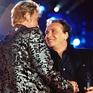 Michel Sardou et Johnny Hallyday sur scène lors d'un concert au Parc de Sceaux, le 16 juin 2000.