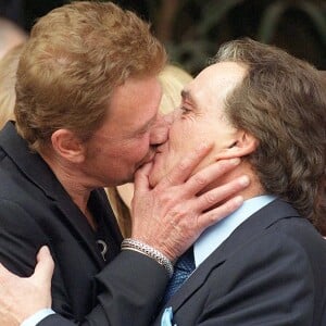 Johnny Hallyday embrasse Michel Sardou en 1999