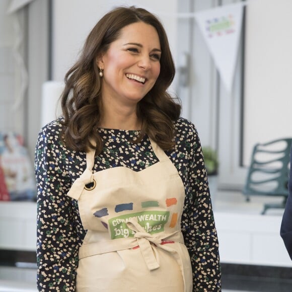 La duchesse Catherine de Cambridge, enceinte, et le prince William ont pris part aux préparatifs du Commonwealth Big Lunch le 22 mars 2018 au centre communautaire St Luke à Londres. Son ultime engagement avant son congé maternité, Kate l'aura accompli... en tablier !