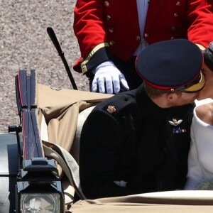 Le prince Harry et Meghan Markle s'embrassent lors de leur procession à travers Windsor le 19 mai 2018 après leur mariage en la chapelle St George.