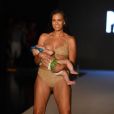 La maman mannequin Mara Martin allaite sa fille Aria, âgée de 5 mois, sur le podium  du défilé Sports Illustrated Swimsuit à la Paraison Fashion Fair à Miami, le 15 juillet 2018.