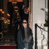 Kim Kardashian quitte le Ritz pour se rendre au restaurant Ferdi, elle porte un long manteau de laine, une combinaison transparente à paillettes argentées et des escarpins à noeuds, Paris, le 25 mars 2019.