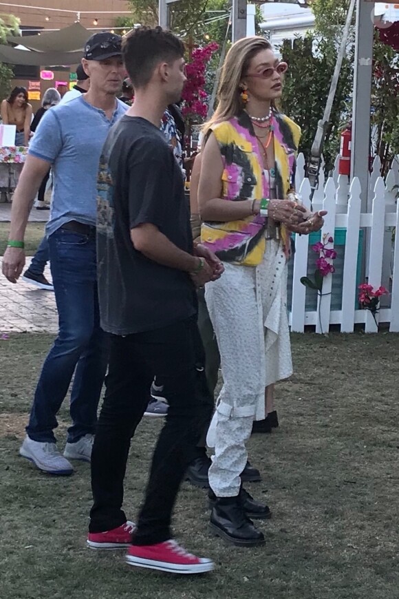 Exclusif - Gigi Hadid porte une veste en jean tye and dye, un pantalon blanc et une paire de boots noires en cuir au festival Coachella, Indio, le 12 avril 2019.