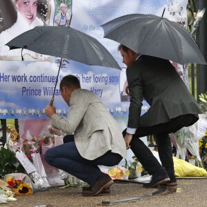 Le prince William et le prince Harry, le 30 août 2017, observant les témoignages d'affection du public à la mémoire de Lady Di sur les grilles du palais de Kensington, à la veille du 20e anniversaire de sa mort.