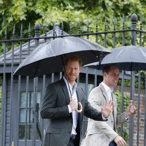Le prince William et le prince Harry, le 30 août 2017, observant les témoignages d'affection du public à la mémoire de Lady Di sur les grilles du palais de Kensington, à la veille du 20e anniversaire de sa mort.