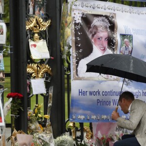 Le prince William et le prince Harry, le 30 août 2017, observant les témoignages d'affection du public à la mémoire de Lady Di sur les grilles du palais de Kensington, à la veille du 20e anniversaire de sa mort.