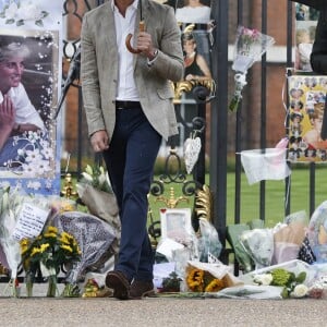 Le prince William et le prince Harry, le 30 août 2017, observant les témoignages d'affection du public à la mémoire de Lady Di sur les grilles du palais de Kensington, à la veille du 20e anniversaire de sa mort.