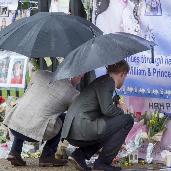 Le prince William et le prince Harry, le 30 août 2017, observant les témoignages d'affection du public à la mémoire de Lady Di sur les grilles du palais de Kensington, à la veille du 20e anniversaire de sa mort.