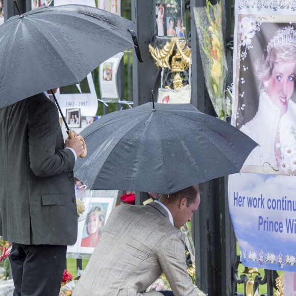 Le prince William et le prince Harry, le 30 août 2017, observant les témoignages d'affection du public à la mémoire de Lady Di sur les grilles du palais de Kensington, à la veille du 20e anniversaire de sa mort.