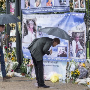 Le prince William et le prince Harry, le 30 août 2017, observant les témoignages d'affection du public à la mémoire de Lady Di sur les grilles du palais de Kensington, à la veille du 20e anniversaire de sa mort.