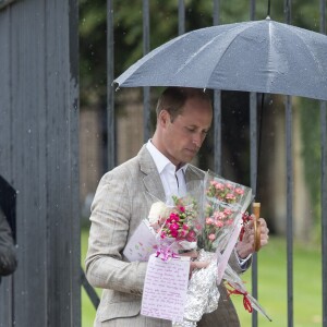 Le prince William et le prince Harry, le 30 août 2017, observant les témoignages d'affection du public à la mémoire de Lady Di sur les grilles du palais de Kensington, à la veille du 20e anniversaire de sa mort.