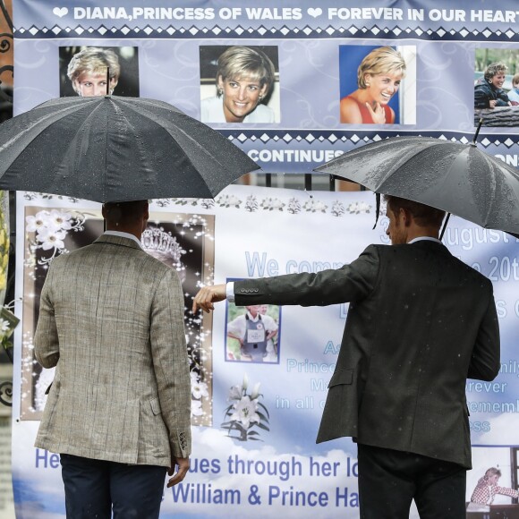 Le prince William et le prince Harry, le 30 août 2017, observant les témoignages d'affection du public à la mémoire de Lady Di sur les grilles du palais de Kensington, à la veille du 20e anniversaire de sa mort.