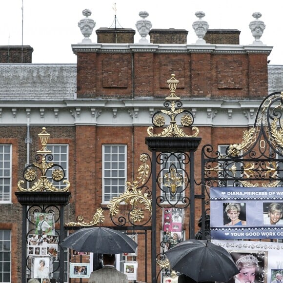 Le prince William et le prince Harry, le 30 août 2017, observant les témoignages d'affection du public à la mémoire de Lady Di sur les grilles du palais de Kensington, à la veille du 20e anniversaire de sa mort.