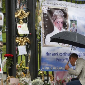 Le prince William et le prince Harry, le 30 août 2017, observant les témoignages d'affection du public à la mémoire de Lady Di sur les grilles du palais de Kensington, à la veille du 20e anniversaire de sa mort.