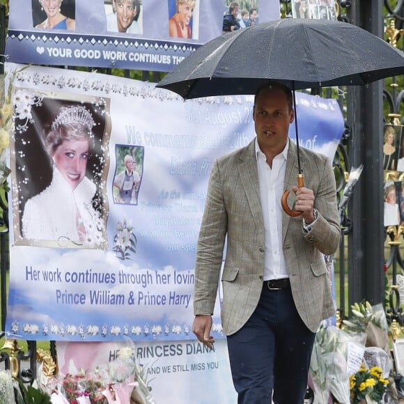 Le prince William et le prince Harry, le 30 août 2017, observant les témoignages d'affection du public à la mémoire de Lady Di sur les grilles du palais de Kensington, à la veille du 20e anniversaire de sa mort.