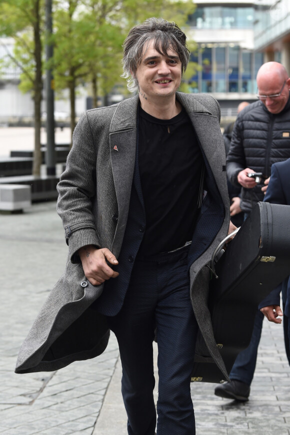 Le rocker Pete Doherty quitte les studios de la BBC après l'enregistrement de l'émission Radio Five Live, il porte un long manteau ulster en laine gris et l'étui de sa guitare à la main. Salford, le 9 mai 2019.