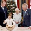 Le prince George de Cambridge prépare, sous le regard bienveillant du prince William, duc de Cambridge, du prince Charles, prince de Galles et de la reine Elisabeth II, des puddings de Noël, dans le cadre du lancement de l'initiative 'Together at Christmas' de la Royal British Legion au Palais de Buckingham, le 21 décembre 2019.