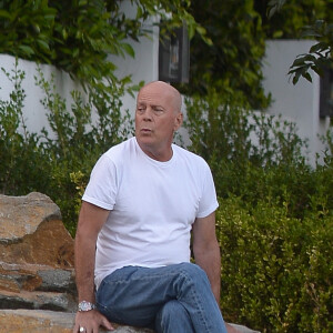 Exclusif - Bruce Willis est assis pieds nus sur un rocher et regarde passer les voitures sur Sunset Boulevard à Los Angeles, le 22 septembre 2019.