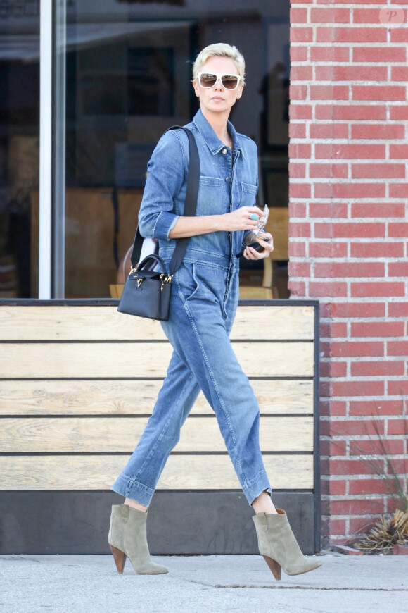 Exclusif - Charlize Theron porte une combinaison pantalon en jean et des bottines en daim pour aller déjeuner au restaurant Sugarfish à Los Angeles, le 3 mars 2020