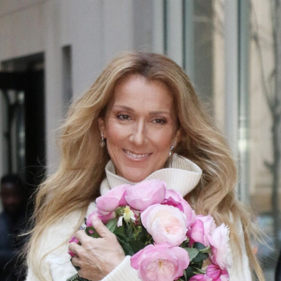 Celine Dion rayonnante et très souriante dans un ensemble pull écru et jupe bouffante fleurie salue ses fans à la sortie de son hôtel à New York, le 8 mars 2020