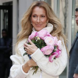 Celine Dion rayonnante et très souriante dans un ensemble pull écru et jupe bouffante fleurie salue ses fans à la sortie de son hôtel à New York