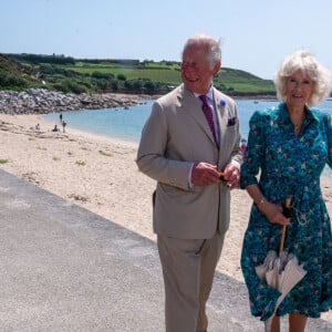 Le prince Charles et Camilla Parker Bowles, la duchesse de Cornouailles se promènent le long de la plage à St Mary's lors de leur visite aux îles Scilly, le 20 juillet 2021.