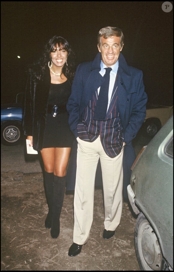 Archives - Jean-Paul Belmondo et sa compagne Carlos Sotto Mayor lors de la générale du spectacle de Thierry Le Luron à Paris. 1983.