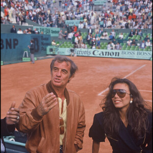 Archives - Jean-Paul Belmondo et sa compagne Carlos Sotto Mayor à Roland-Garros en 1986.