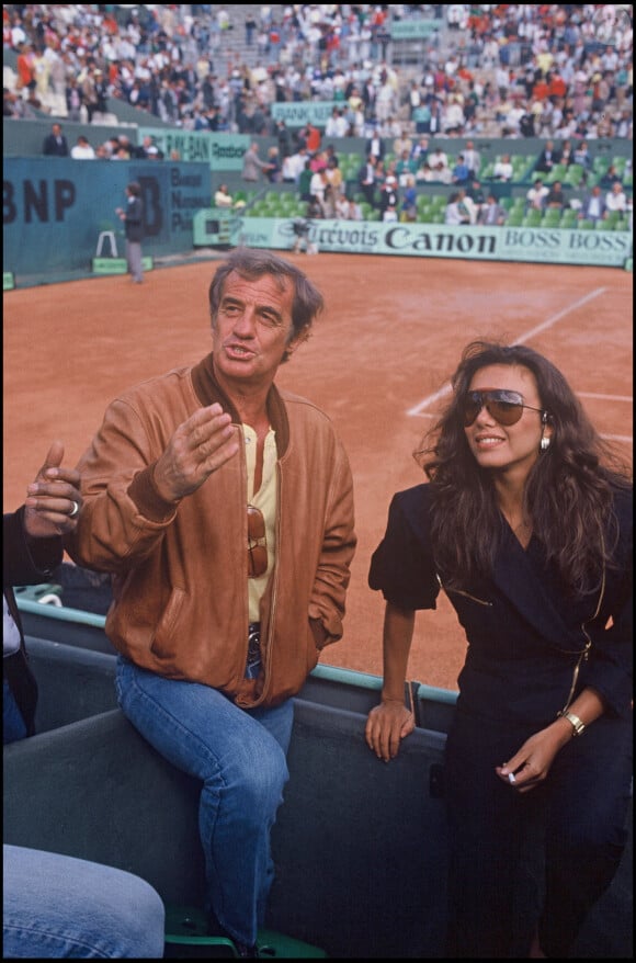 Archives - Jean-Paul Belmondo et sa compagne Carlos Sotto Mayor à Roland-Garros en 1986.