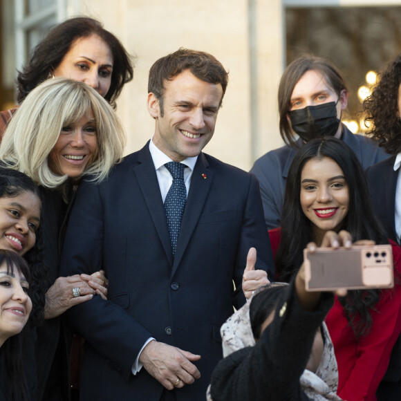 Le président de la République française, Emmanuel Macron et sa femme la Première Dame, Brigitte Macron posent pour une photo de groupe avec les premières lauréates de l'Initiative Marianne pour les défenseurs des droits de l'homme à la suite d'une cérémonie de remise de prix dans le cadre de la journée internationale de la femme, au palais de l'Elysée à Paris, France, le 8 mars 2022.