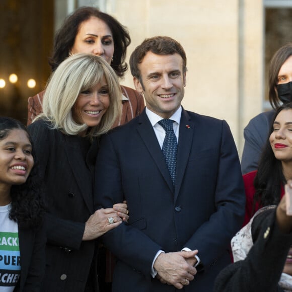 Le président de la République française, Emmanuel Macron et sa femme la Première Dame, Brigitte Macron posent pour une photo de groupe avec les premières lauréates de l'Initiative Marianne pour les défenseurs des droits de l'homme à la suite d'une cérémonie de remise de prix dans le cadre de la journée internationale de la femme, au palais de l'Elysée à Paris, France, le 8 mars 2022.