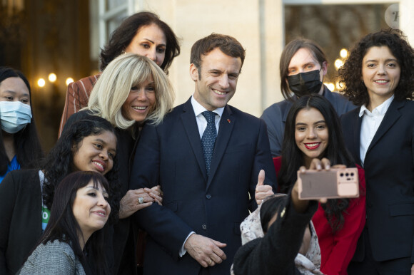 Le président de la République française, Emmanuel Macron et sa femme la Première Dame, Brigitte Macron posent pour une photo de groupe avec les premières lauréates de l'Initiative Marianne pour les défenseurs des droits de l'homme à la suite d'une cérémonie de remise de prix dans le cadre de la journée internationale de la femme, au palais de l'Elysée à Paris, France, le 8 mars 2022.