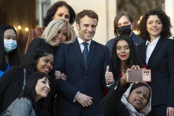 Le président de la République française, Emmanuel Macron et sa femme la Première Dame, Brigitte Macron, très complices, posent pour une photo de groupe avec les premières lauréates de l'Initiative Marianne pour les défenseurs des droits de l'homme à la suite d'une cérémonie de remise de prix dans le cadre de la journée internationale de la femme, au palais de l'Elysée à Paris