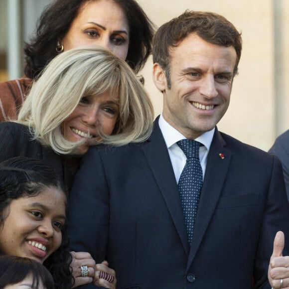 Le président de la République française, Emmanuel Macron et sa femme la Première Dame, Brigitte Macron, très complices, posent pour une photo de groupe avec les premières lauréates de l'Initiative Marianne pour les défenseurs des droits de l'homme à la suite d'une cérémonie de remise de prix dans le cadre de la journée internationale de la femme, au palais de l'Elysée à Paris